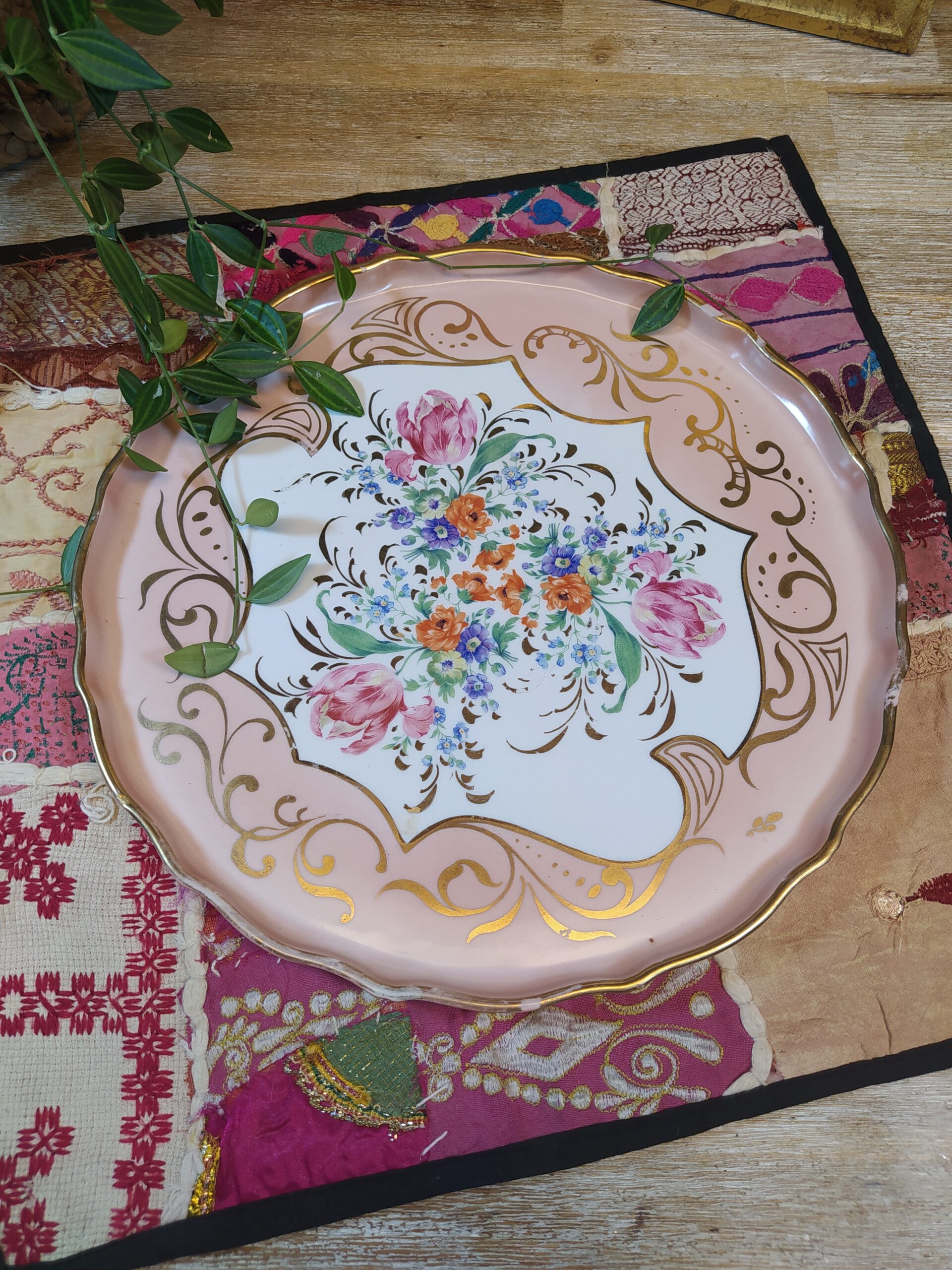 Jolie assiette aux bords hauts en porcelaine vintage de la manufacture de Couleuvre, avec ses motifs floraux et ses arabesques dans des teintes roses et dorées.