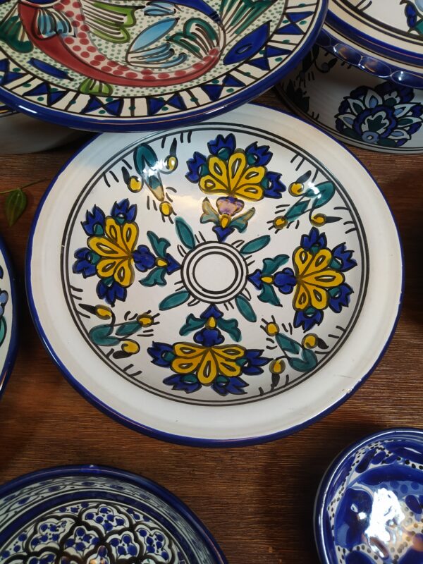Assiette creuse en céramique motifs orientaux de fleurs en jaune, bleu et vert.